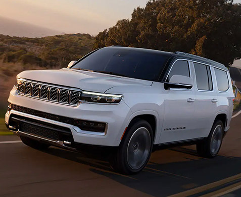 2022 Jeep Grand Wagoneer driving at sunset on road