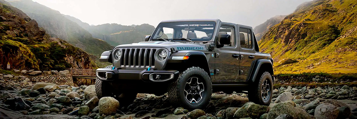 A 2022 Jeep Wrangler Rubicon 4xe parked on a rocky plateau, surrounded by mountains.