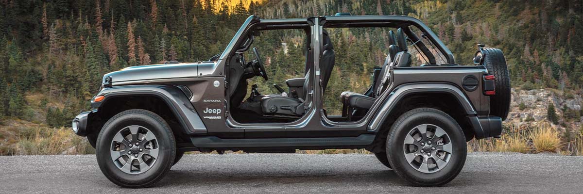 2022 Jeep Wrangler with doors and roof removed on a road in front of mountainous terrain