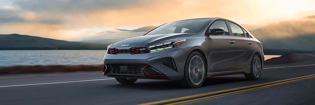 2022 Kia Forte in gray, action shot on coastal highway with view of front and driver side