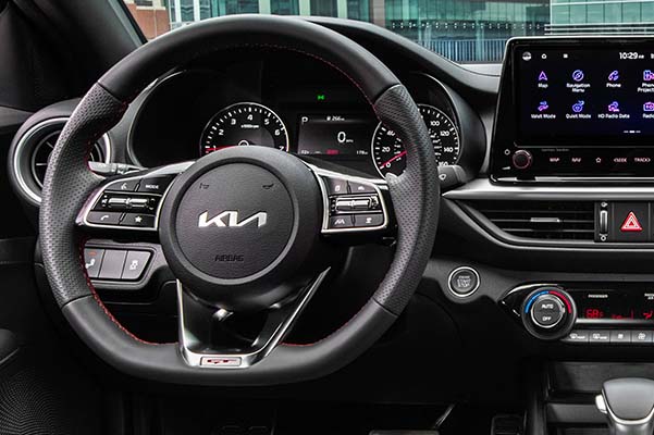 2022 Kia Forte, close-up shot of steering wheel, center console features, infotainment screen applications, and push to start ignition