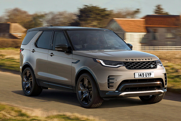 A 2022 LAND ROVER DISCOVERY driving down a road with houses in the background