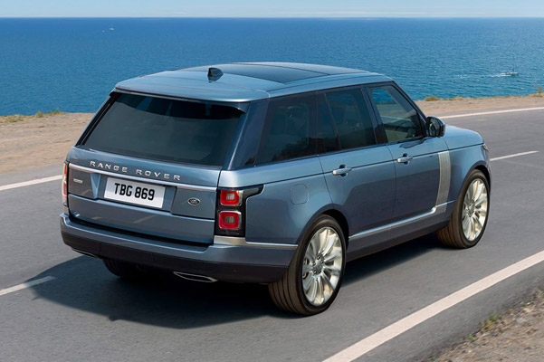 Exterior rear shot of a 2022 Range Rover driving down a road with an ocean in the background.