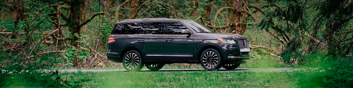 A 2022 Lincoln Navigator in a lush forest setting shows off the exterior design of the Lincoln Black Label Central Park theme