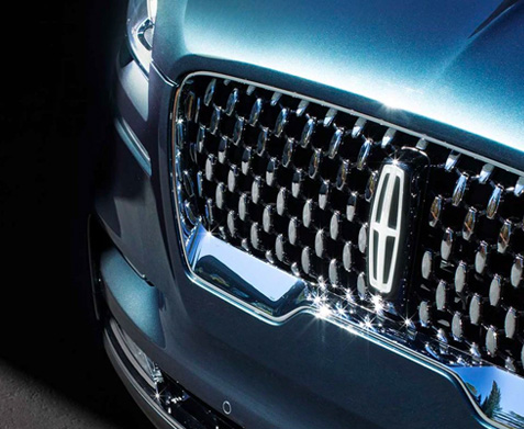 The grille of a Lincoln Black Label vehicles beams radiantly in the sunshine