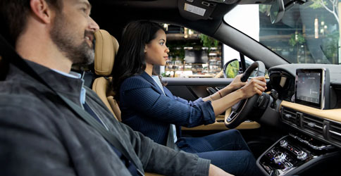 A couple is driving a 2022 Lincoln Corsair through the city during the day using Lincoln plus Alexa to find information