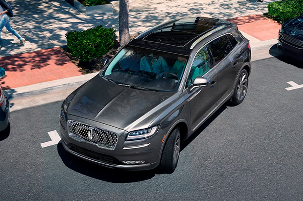 A 2022 Lincoln Nautilus is shown being parallel parked in a quaint city shopping area