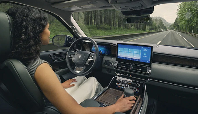 A woman in the driver seat of a 2022 Lincoln Navigator Black Label relaxes with hands-free driving technology engaged