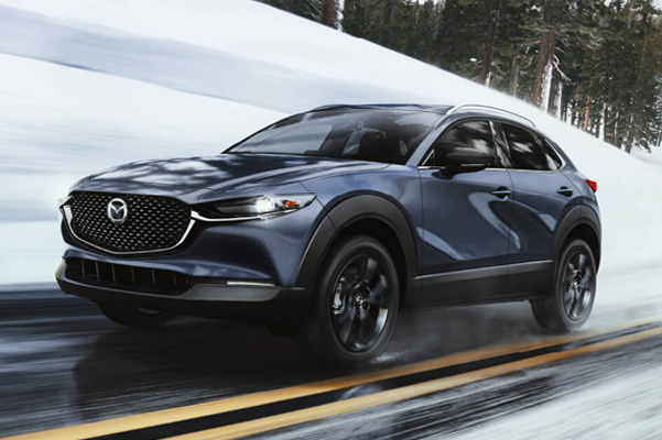 2022 Mazda CX-30 driving down wet road in snowy hills during the day