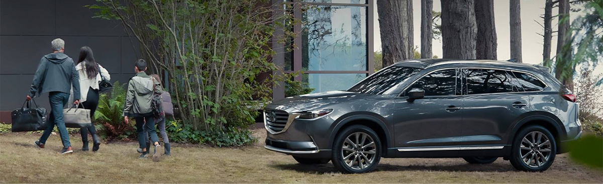 2022 Mazda CX-9 parked outside with a family walking towards a modern home