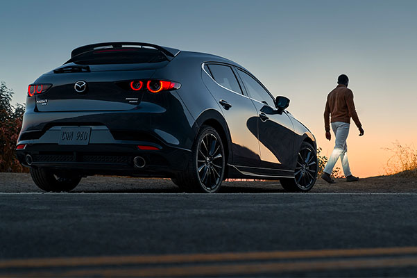 2022 Mazda3 Hatchback with driver standing looking into sunset