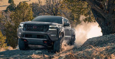 The 2022 Nissan Frontier driving up a dirt hill