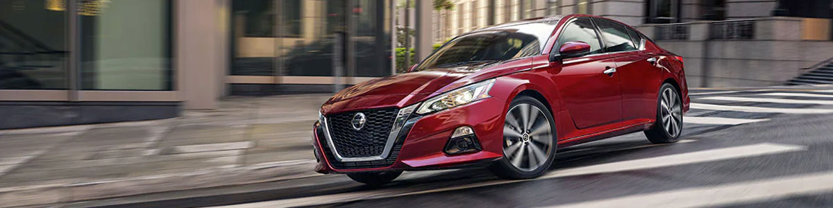 2022 Nissan Altima in red making a fast turn on downtown street.