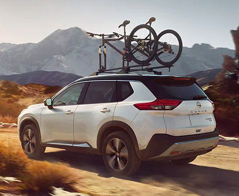 2022 Nissan Rogue driving on trail with bikes on rack