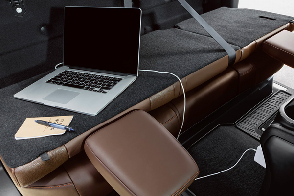 The backseat of the 2022 Nissan TITAN folded down into a workbench with a charging laptop