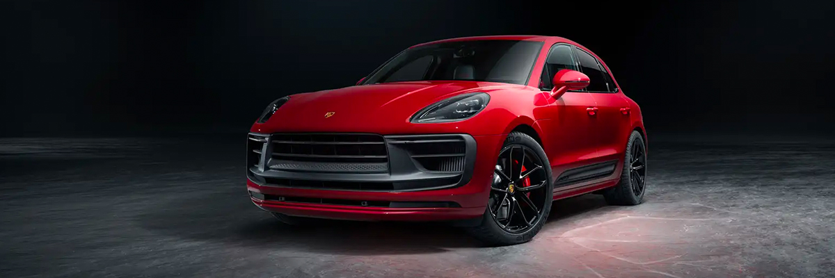 A red 2022 Porsche Macan parked in a dark studio.