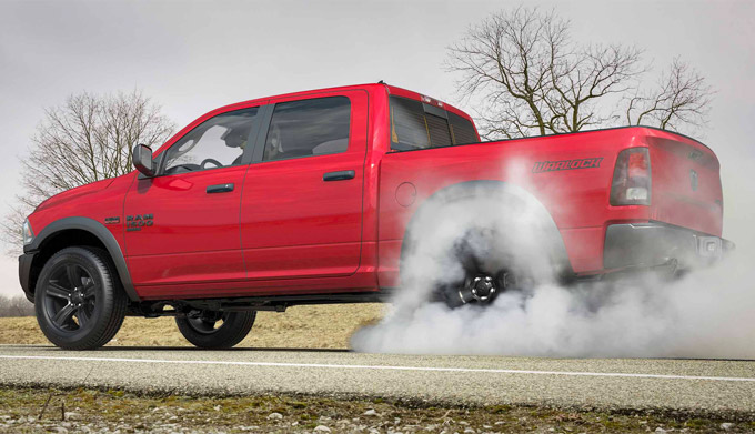Display A 2022 Ram 1500 Classic doing a burnout on an empty road.
