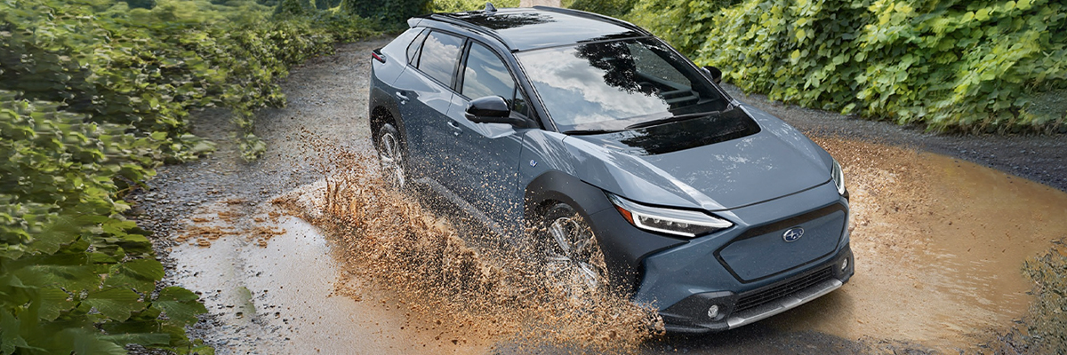The 2023 Subaru Solterra driving through a puddle of mud