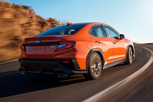 Limited shown in Solar Orange Pearl driving away on a road in the mountains