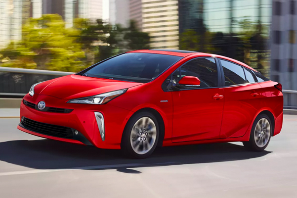 Exterior shot of a red 2022 Toyota Prius driving in a city.