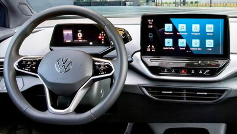 An interior shot of an ID.4 with focus on the steering wheel, driver display, center console display and front windshield.
