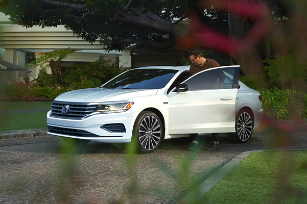 Exterior shot of a 2022 Volkswagen Passat parked in a driveway with a person entering the vehicle.