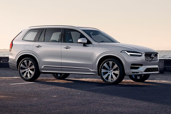 A Volvo XC90 parked on a road by the sea.