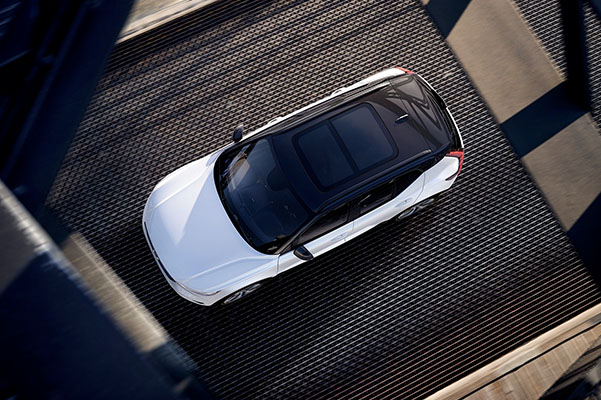 Open-and-tilt panoramic roof of a white XC40 Recharge seen from above.
