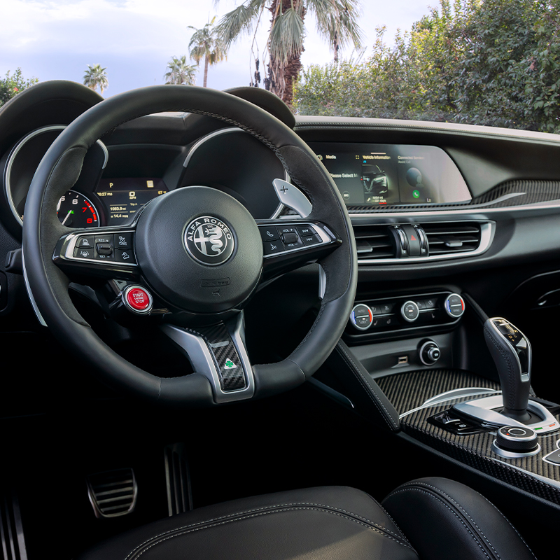2023 Stelvio Quadrifoglio interior in black leather, view from driver's seat featuring steering wheel and center console.