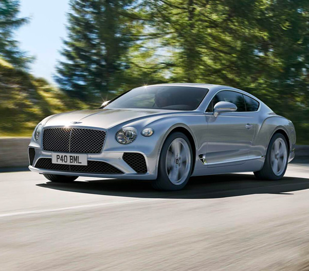 2023 Bentley Continental GT driving down a road with trees in the background