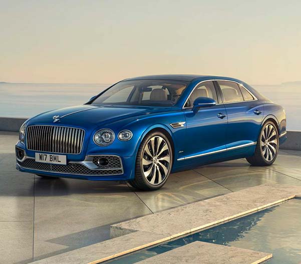 Exterior shot of a 2023 Bentley Flying Spur parked on a marble platform with an ocean in the background.