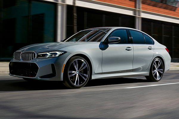 Exterior shot of a 2023 BMW 3 Series driving on a city street.