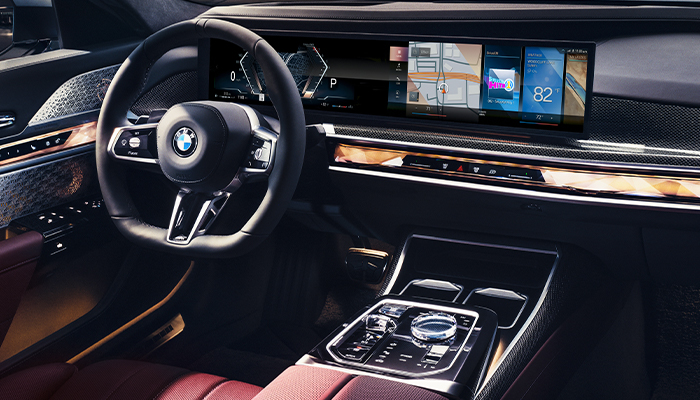 BMW 7 Series Car Dashboard interior with steering wheel and curved screen, red details