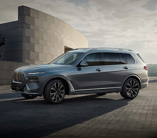 A side exterior shot of the 2023 BMW X7 Sports Activity Vehicle in Sparkling Copper Metallic parked on a paved road in a desert setting