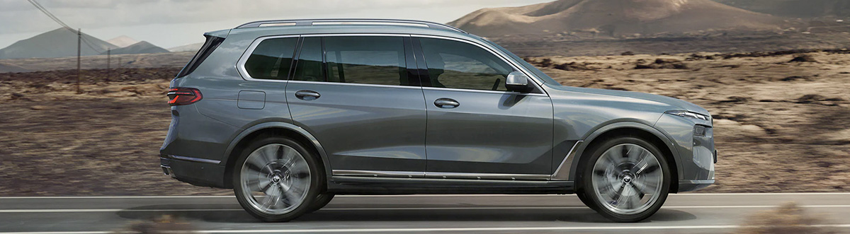 A side exterior shot of the 2023 BMW X7 Sports Activity Vehicle in Sparkling Copper Metallic drives down a desert road