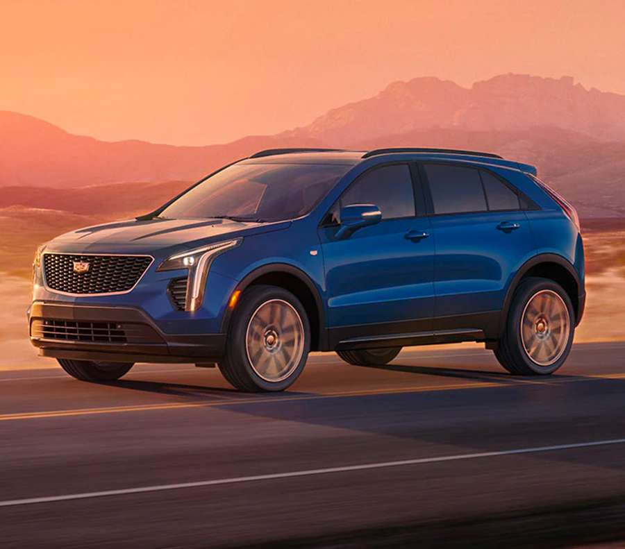 Side shot of 2023 Cadillac XT4 driving in valley during dusk.