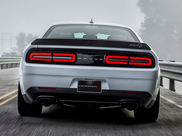 The rear of a white 2023 Dodge Challenger SRT Hellcat stopped on a highway with its taillamps on.