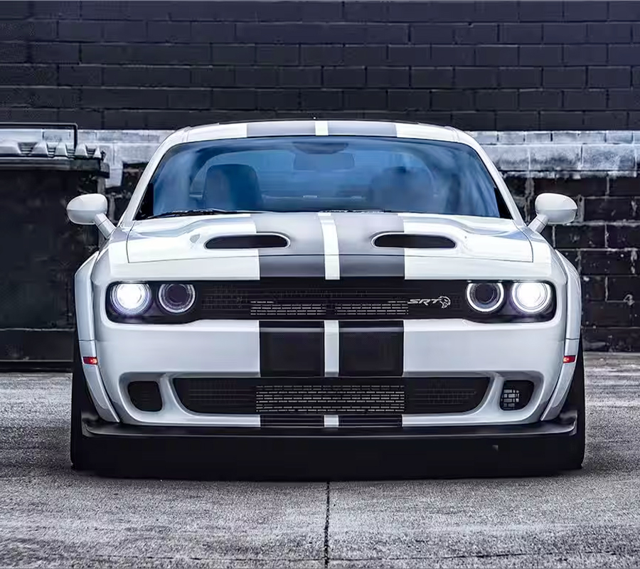 A white 2023 Dodge Challenger SRT Hellcat with black center stripes, parked in an alley.