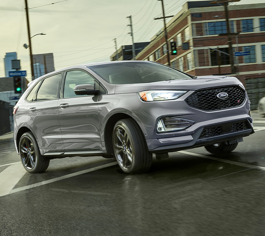 2023 Ford Edge® ST SUV in Iconic Silver turning right on a wet street