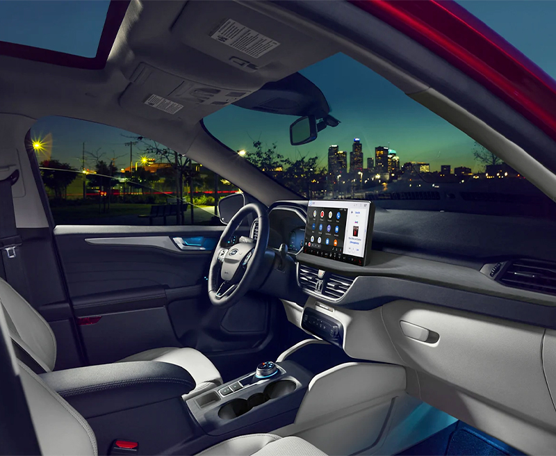 2023 Ford Escape® in Rapid Red at night, passenger side door open with cityscape in background