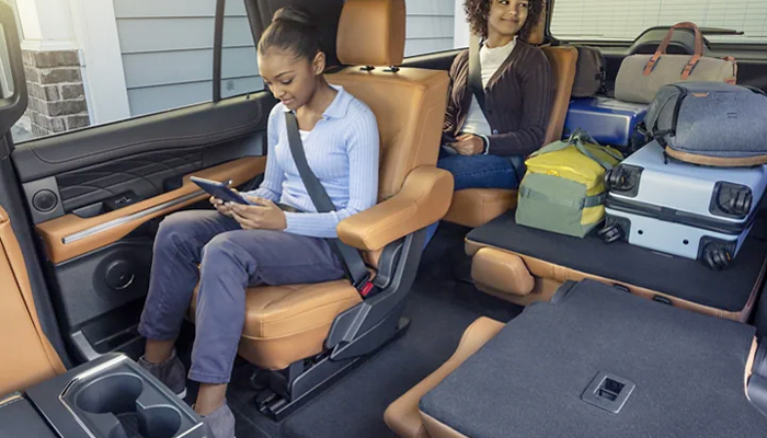 A young girl looking at her tablet in the back seat of a 2023 Ford Expedition SUV