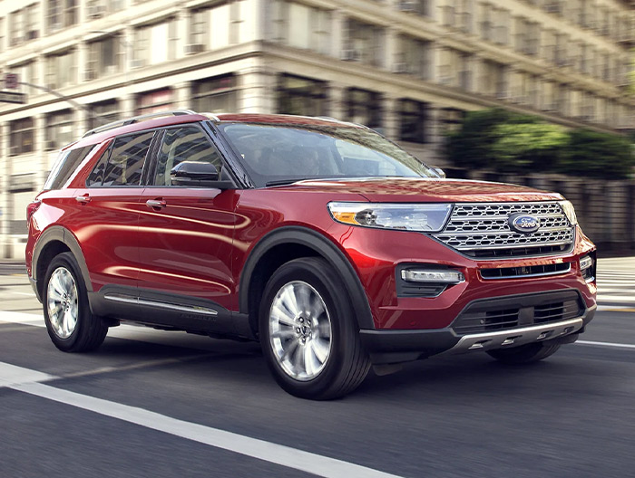 2023 Ford Explorer® Limited model in Rapid Red Metallic Tinted Clearcoat being driven down a city street