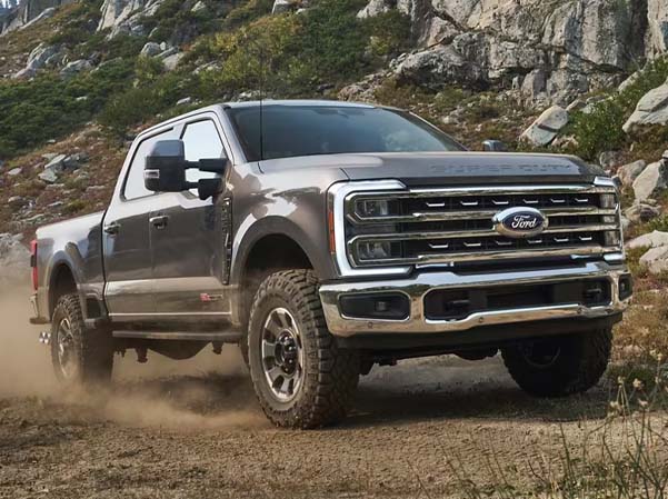 Exterior shot of a 2023 Ford Super Duty® F-350 driving on dirt on a sunny day.