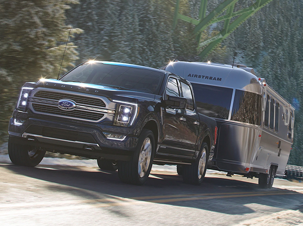 A 2023 Ford F-150® towing a camper up an inclined road