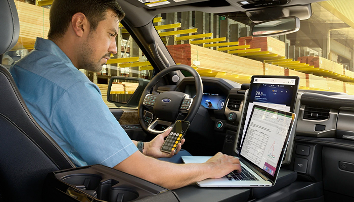Interior of a 2023 Ford F-150 Lightning® with man working on his computer on the work surface