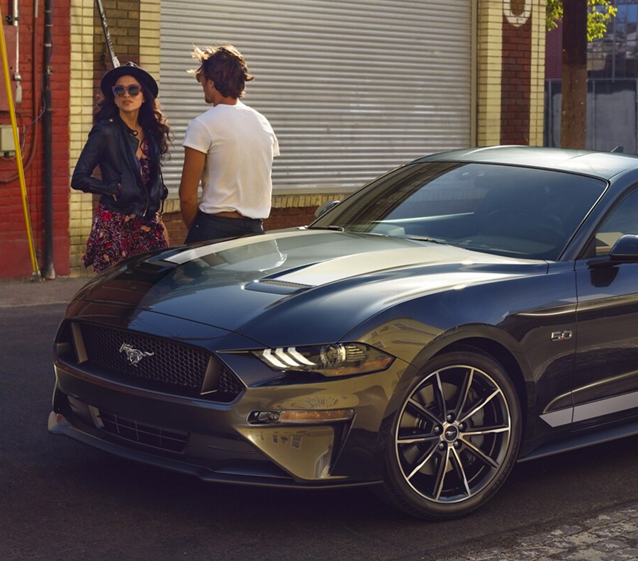 Man and woman standing around Ford Mustang