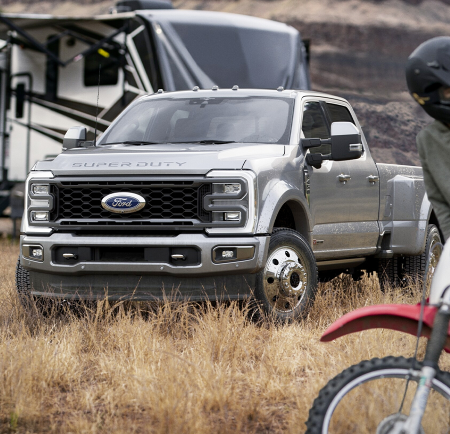 2023 Ford Super Duty® F-450® Limited Crew in Iconic Silver Metallic hitched to a camper trailer