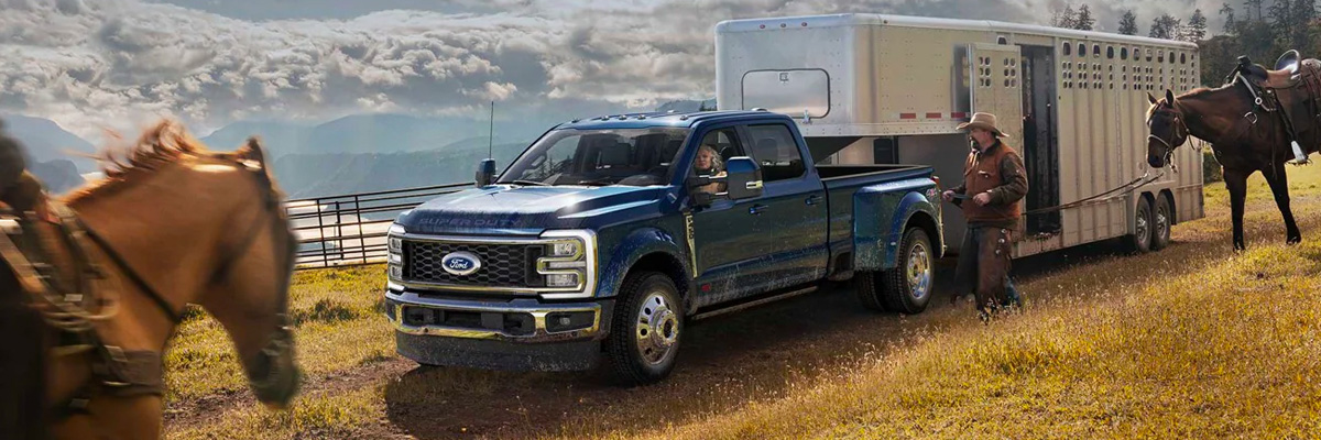 A man riding a horse toward a 2023 Ford Super Duty® F-450® King Ranch® DRW hitched to a horse trailer
