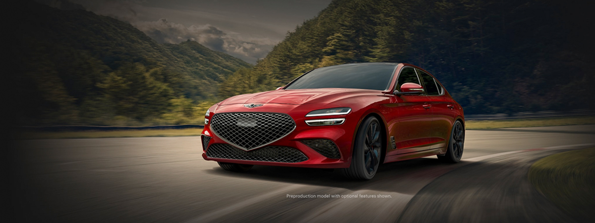 The 2023 Genesis G70 taking a turn on a road with mountains in the background.