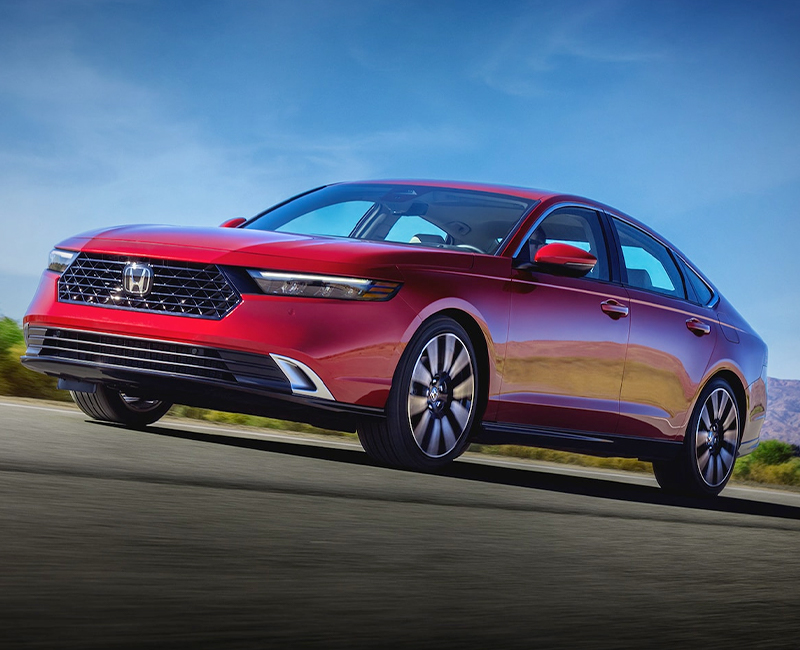 Front driver-side view of the 2023 Honda Accord in Radiant Red Metallic driving in the desert.